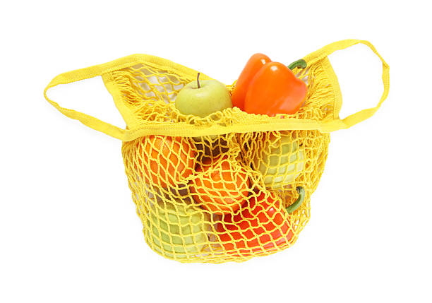 Fresh products in yellow string bag isolated on white, top view