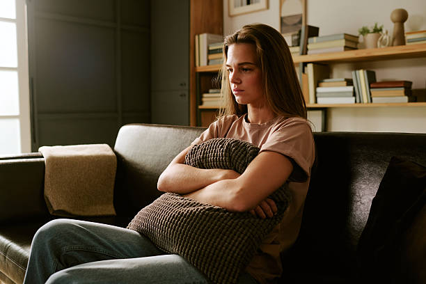 istock Young Caucasian Woman Sitting Alone on Sofa Hugging Pillow Feeling Anxious 2247077546