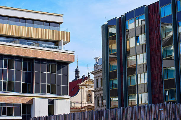 Modern residential and office buildings with glass facades near historic architecture in Prague. Concept of urban contrast, city development and mixed architecture