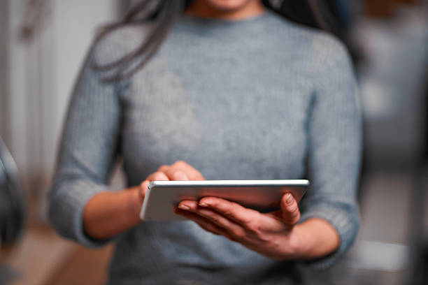 istock Woman Using Tablet Device In Soft Gray Sweater, Focused On Digital Task 2247083935