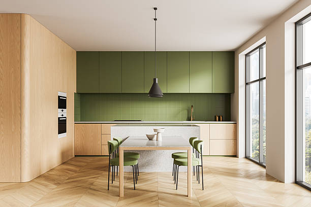 istock Modern kitchen interior with green cabinets, wooden textures, large windows, and minimalist dining setup in bright natural lighting. 3D Rendering 2247085883