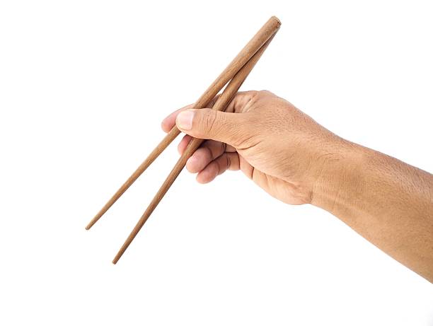 istock Man hand holding wooden chopsticks isolated on white background 2247087085