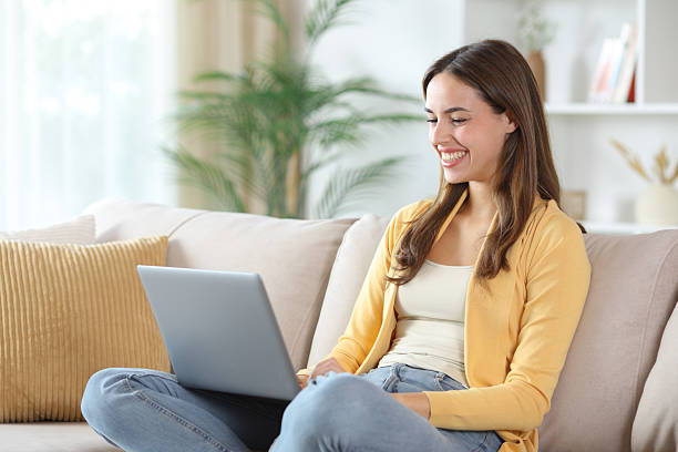 istock Happy woman in yellow using laptop at home 2247087109