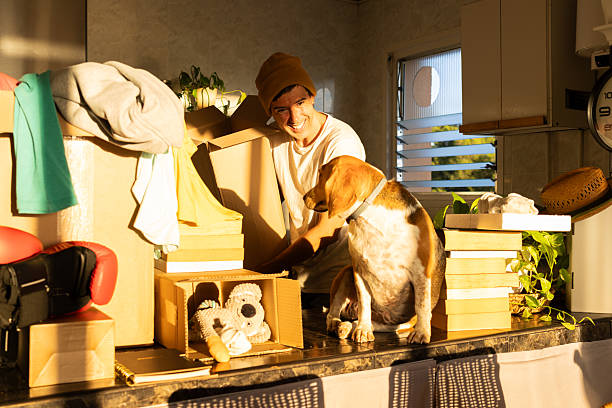 istock Man and dog packing moving boxes at sunset 2247087173