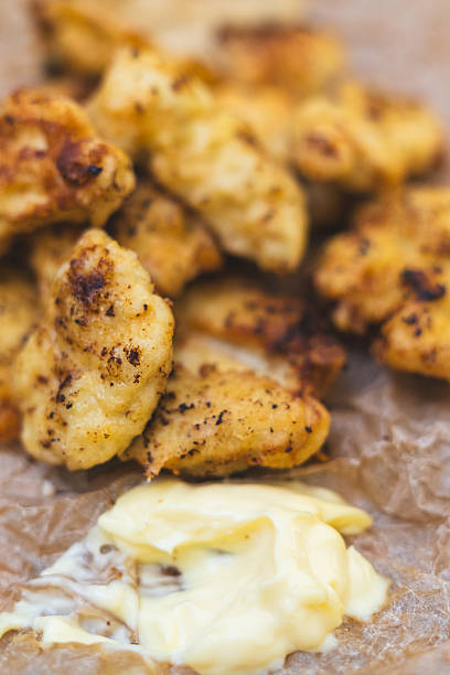 Close-up of golden homemade chicken nuggets arranged on a wooden board. Macro photography highlights the texture, coating, and homemade freshness.