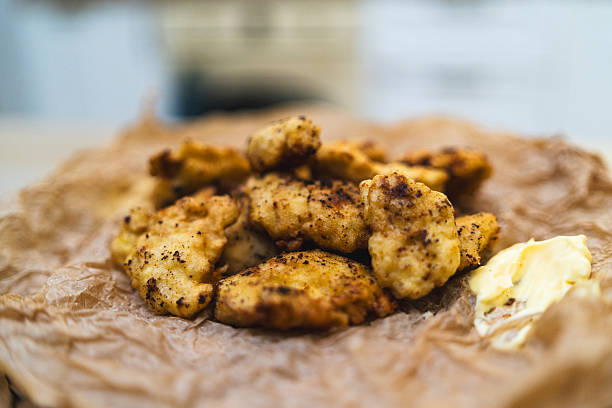 Close-up of crispy homemade chicken nuggets served with a dipping sauce. The golden coating and juicy interior are emphasized, perfect for food blogs or stock photography.