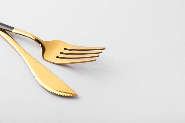istock Stylish cutlery. Golden knife and fork on gray background, closeup. Space for text 2247090421