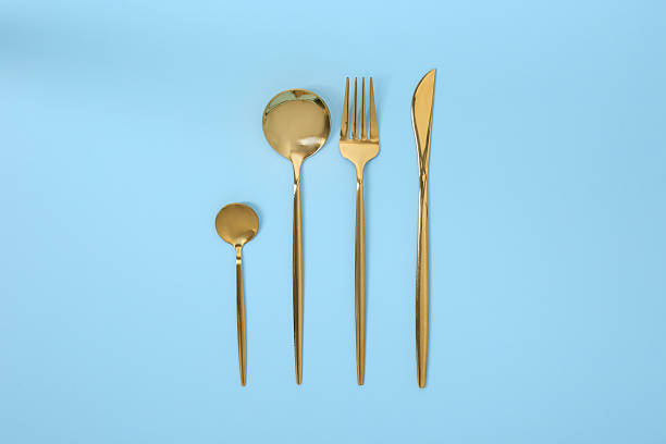 istock Stylish golden cutlery set on light blue background, flat lay 2247090429