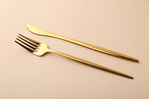 istock Stylish cutlery. Golden knife and fork on beige background 2247090432
