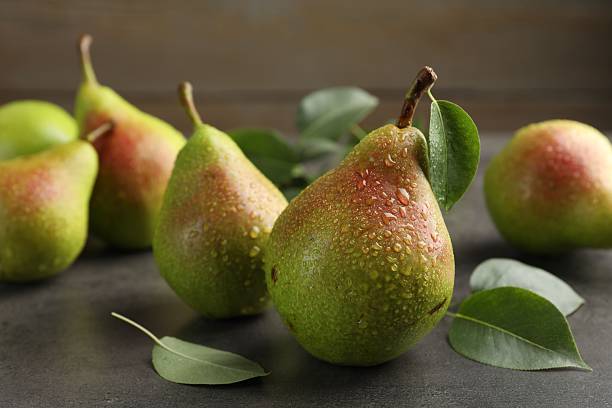 istock Fresh ripe pears and green leaves on grey table, closeup 2247090738