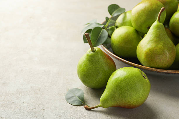 istock Fresh ripe pears and green leaves on light grey table, closeup. Space for text 2247090757