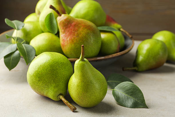 istock Fresh ripe pears and green leaves on light grey table, closeup 2247090956