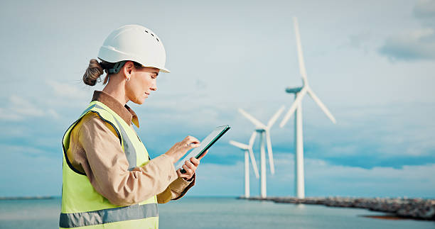 istock Worker, woman and typing with tablet for wind turbine performance, log maintenance or reporting. Windmill energy, technician and tech on offshore power plant for routine inspection or troubleshooting 2247090998