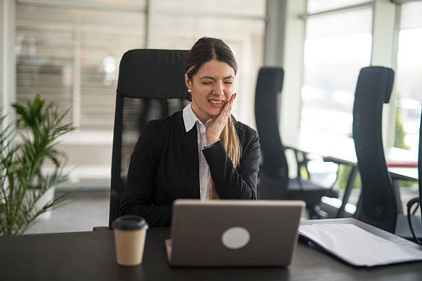 istock Businesswoman suffering from toothache while working on laptop in office 2247091651