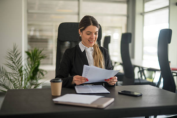 istock Businesswoman smiling while reviewing documents at her desk 2247091759