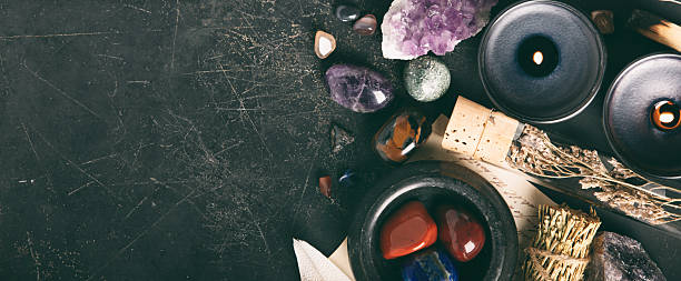 An arrangement of healing crystals, herb bundles, and essential oils placed on a textured dark background, perfect for holistic wellness themes.