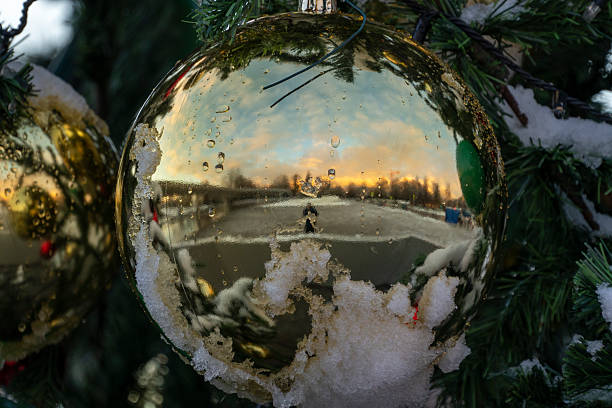 A gold ornament with a reflection of a snowy landscape. The reflection shows a person walking on a snowy road