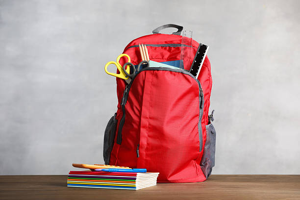 istock Red backpack with different school stationary on wooden table against gray background 2247093753