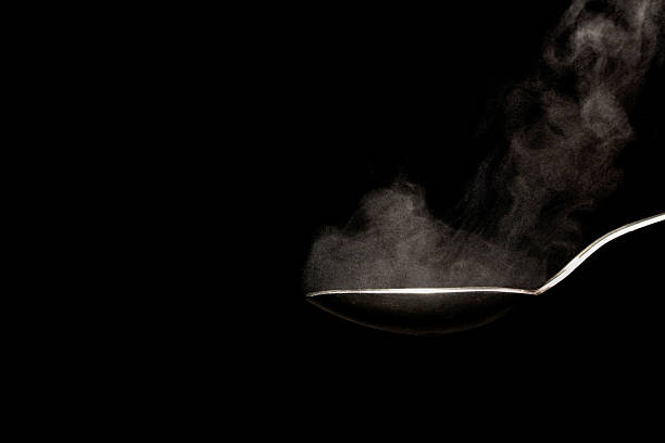hot steel spoon on black background with steam from water