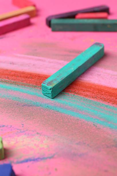 istock Many colorful chalk pastels on pink background, closeup 2247097074
