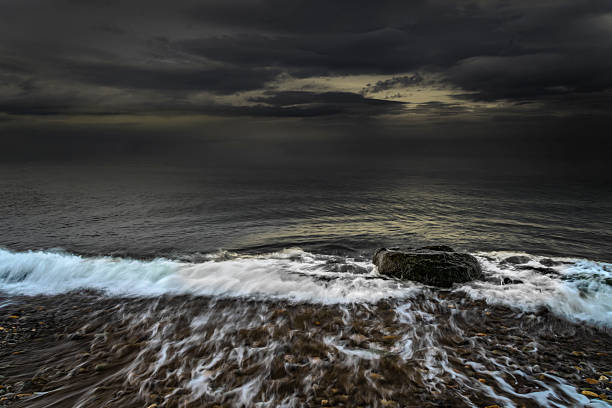 Wild seascape showing breaking wave and dark clouds over rugged irish shoreline