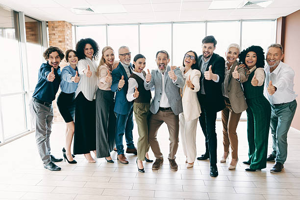 istock Group of professional colleagues giving a thumbs-up gesture in a modern office space promoting teamwork and collaboration 2247100329