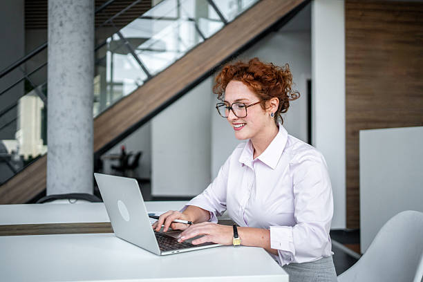 istock Redhead businesswoman smiling while typing on laptop 2247102197