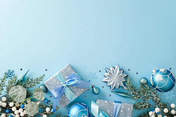 istock Christmas flat lay composition with gift boxes, blue baubles, and a silver star. Festive holiday decor forming a bottom border on a light blue background. Top view with copy space. 2247103164