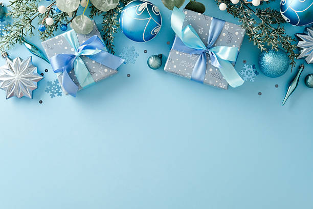 istock Two Christmas gift boxes, fir branches, blue and silver ornaments on light blue background. Xmas greeting card design. 2247103363