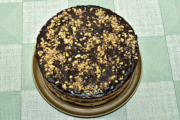 Sponge cake with cream and chocolate fondant, sprinkled with roasted chopped nuts.