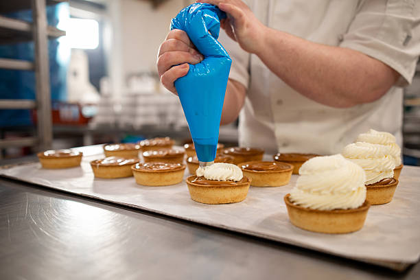 istock Piping Whipped Cream onto Dessert Tarts 2247107111