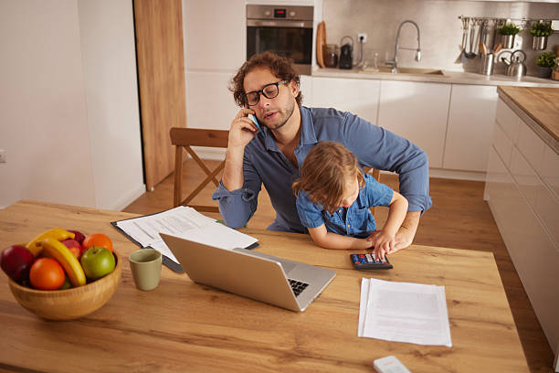 istock Father working from home with child on calculator 2247107369