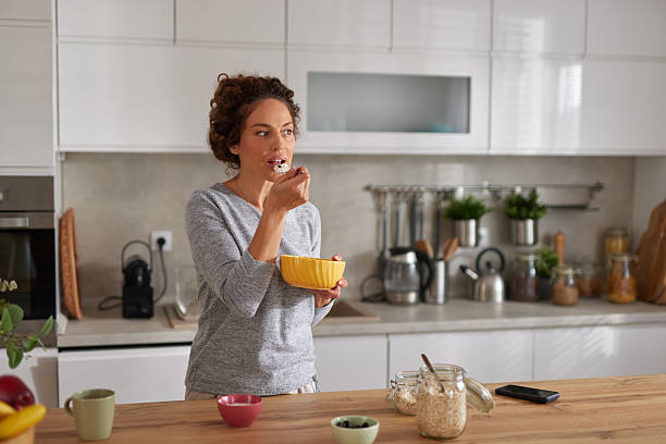 istock Young woman eating healthy breakfast in modern kitchen 2247108696