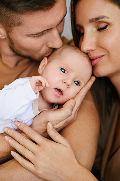 istock Parents Kissing Baby Cheeks With Love 2247109839