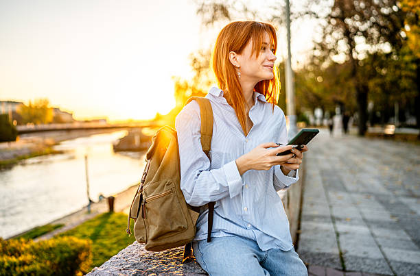 istock Young woman using smartphone outdoors at sunset 2247110984