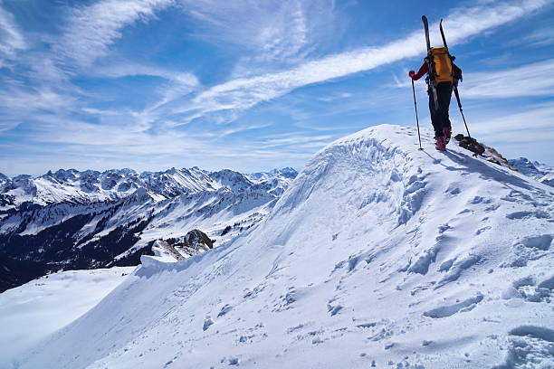 Elderly man sporting fit skis uphill climbing in te alps