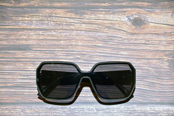 istock Black eyeglasses on a wooden background. Selective focus. Sunglasses with black frame on table. Woman sunglasses. 2247114494