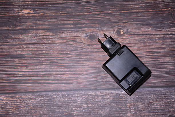 Battery charger. Charging adapter on a wooden texture background