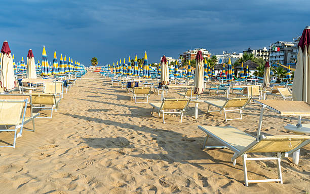 istock Sun loungers on sandy beach with Umbrellas. Empty seaside resort. Italy. 2247117213
