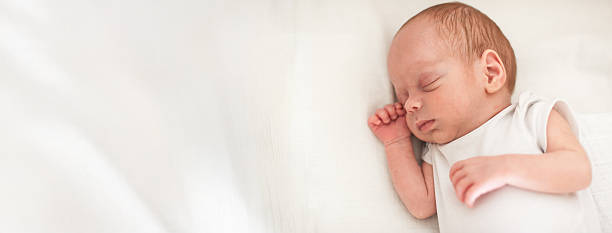 istock Newborn baby peacefully sleeping on soft, white bedding in a calm and serene setting, surrounded by a feeling of tranquility and comfort 2247122344