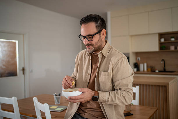 istock Man enjoying healthy breakfast cereal with banana in kitchen 2247124121