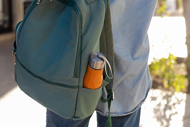 istock Student carrying a green backpack with an orange reusable water bottle, promoting sustainability, education, health, hydration, and an eco-friendly everyday lifestyle outdoors 2247127408