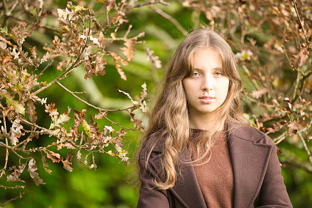 Sixteen year old girl wearing green and brown by an old oak tree.