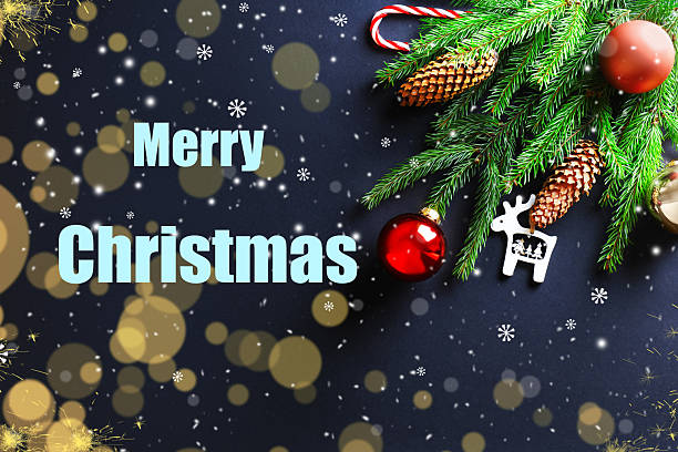 istock Merry Christmas text with snow, light bokeh, fir branches, pine cones, and red bauble ornaments on a dark background. 2247129187
