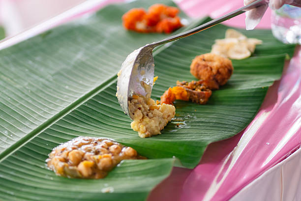 Food placement on banana leaf featuring lentils, snacks, and curry items. South Indian dining tradition, cultural hospitality, and the practice of serving meals on natural leaves.