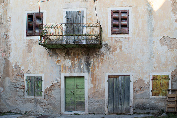 Weathered Facade of an Old Stone House with Rustic Shutters