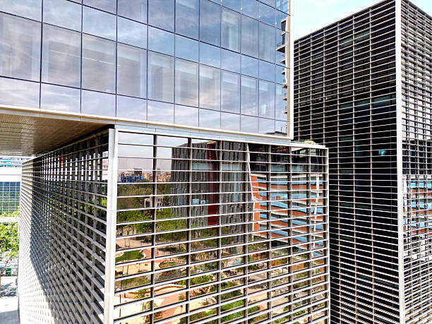 istock Bottom view of office building window close up, reflection and perspective. Modern architecture with sun ray. Glass facade on a bright sunny day with sunbeams on the blue sky. 2247133498