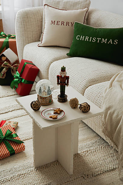 istock Elegant Christmas scene with a small table, nutcracker, snow globe, and festive cookies near a cozy sofa. 2247133975