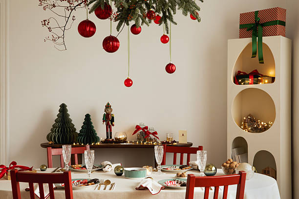 istock Christmas dining room with red chairs, decorated table, and hanging evergreen branches with red ornaments. 2247133986