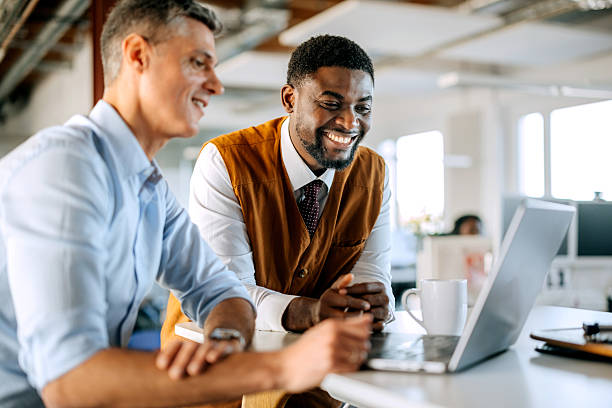 istock Two diverse male colleagues discussing work using laptop in office 2247136506